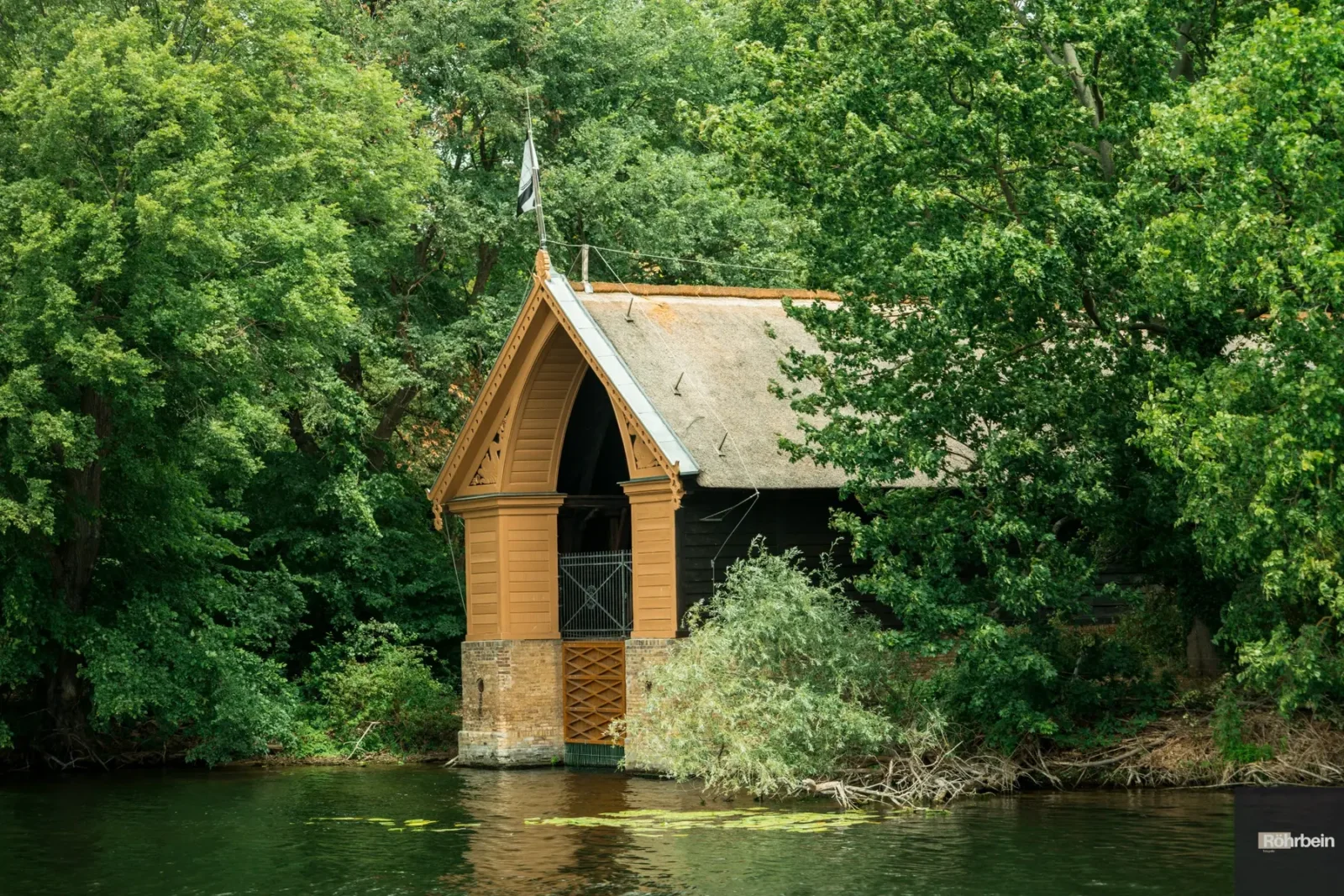 Kleines hölzernes Bootshaus an einem grünen Ufer